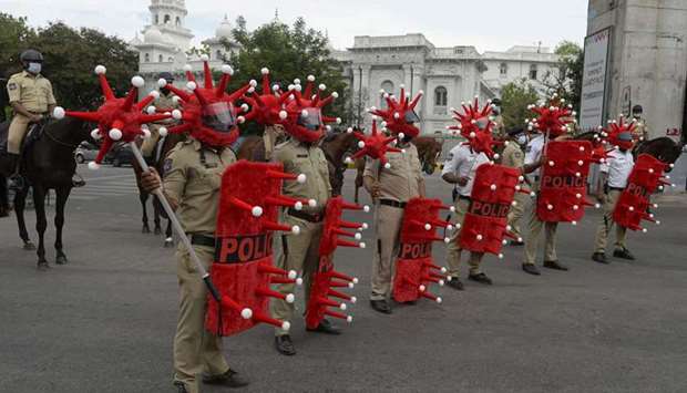 Police personnel wearing a Covid-19 coronavirus-themed helmets, shields and battons stand in formation as they take part in awareness campaign against the pandemic at a traffic junction in Hyderabad