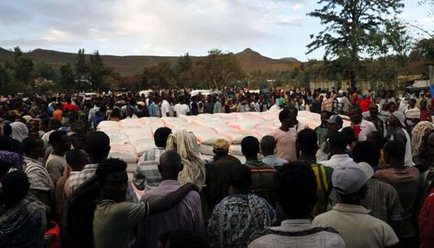 People stand in line to receive food donations, at the Tsehaye primary school, which was turned into a temporary shelter for people displaced by conflict, in the town of Shire, Tigray region, Ethiopia