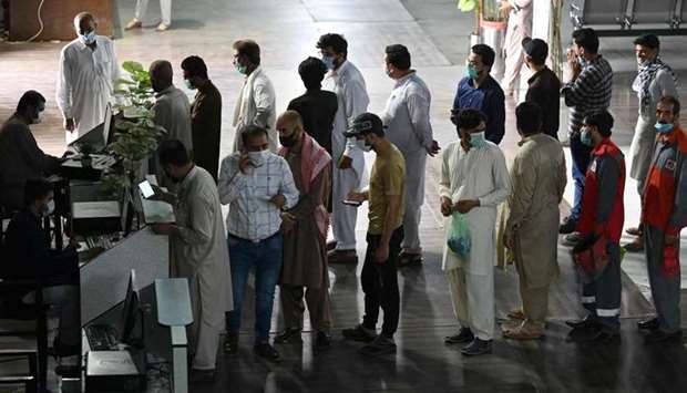 People stand in a queue to register to receive a dose of the Covid-19 coronavirus Sinopharm vaccine at a vaccination center in Rawalpindi.