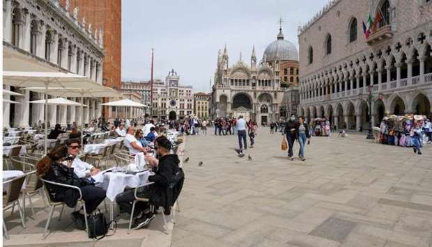 People sit at outdoor tables at St. Mark's Square as Italy lifts quarantine restrictions for travellers arriving from European Union countries, Britain and Israel