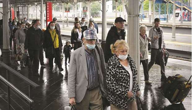 Passengers, mostly unmasked and with some wearing face masks improperly, are seen yesterday on a platform of Belorussky railway station in Moscow.