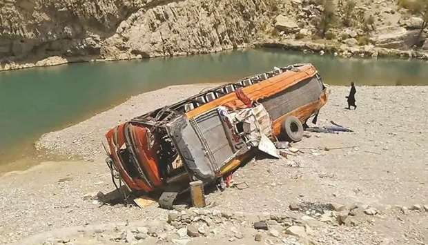 A man walks past a damaged bus in a remote district of Balochistan. The bus carrying dozens of pilgrims plunged into a ravine in southwest Pakistan yesterday, killing at least 18, officials said.