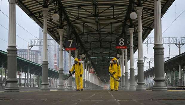 Servicemen of the Russian Ministry for Civil Defence, Emergencies and Elimination of Consequences of Natural Disasters, wearing protective gear, disinfects a railway station.