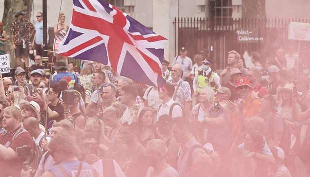 Protesters fly a Union flag as a smoke bomb goes off at a gathering outside Downing Street as they demonstrate against government lockdown restrictions, 5G and Covid-19 vaccinations in central London yesterday.
