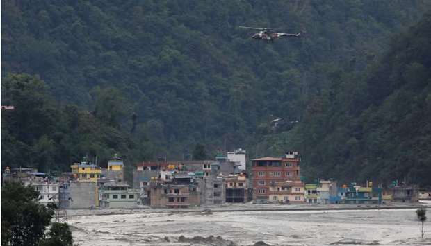 A helicopter belonging to Nepal army flies past houses hit by flash floods along the bank of Melamchi River during a rescue mission in Sindhupalchok, Nepal