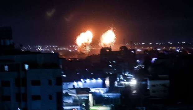 Explosions light-up the night sky above buildings in Gaza City as Israeli forces shell the Palestini