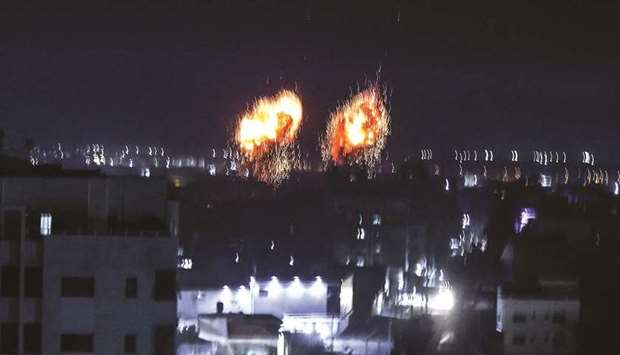 Explosions light-up the night sky above buildings in Gaza City as Israeli forces shell the Palestinian enclave, yesterday.