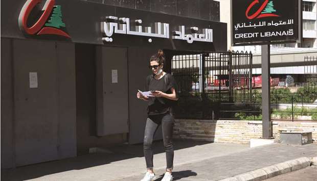 A woman walks past a closed branch of Credit Libanais bank in Beirut yesterday. About 3,000 bankers, or more than 10% of the banking industry workforce, have resigned or lost their jobs so far since a financial crisis flared up in late 2019 u2013 and the numbers keep rising, four senior bankers told Reuters.