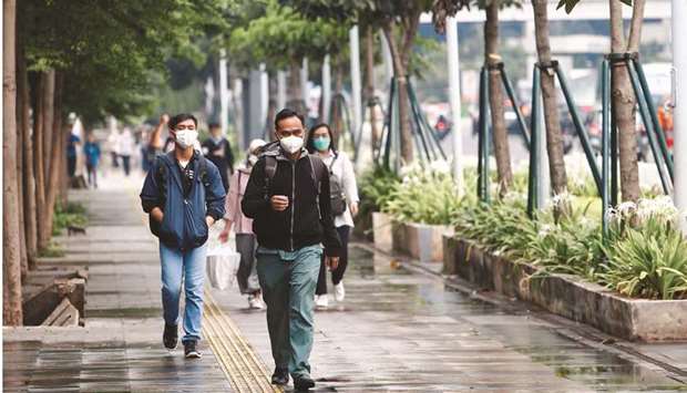 People wearing protective face masks walk on a sidewalk amid the Covid-19 pandemic in Jakarta. A new wave of coronavirus infections threatens to derail the economy, which until recently had been showing signs of turning the corner.