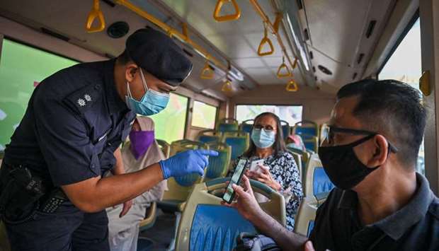 A policeman inspects the travel documents of a passenger on a bus at a roadblock during the nationwide lockdown, amid fears over the spread of the Covid-19 coronavirus, in Kuala Lumpur
