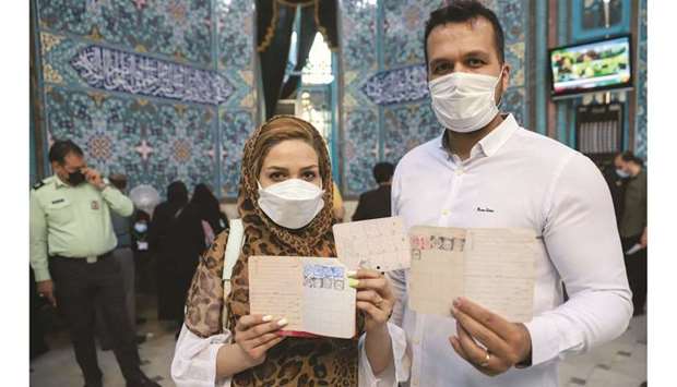 An Iranian couple holds documents after voting during presidential elections at a polling station in Tehran, yesterday.