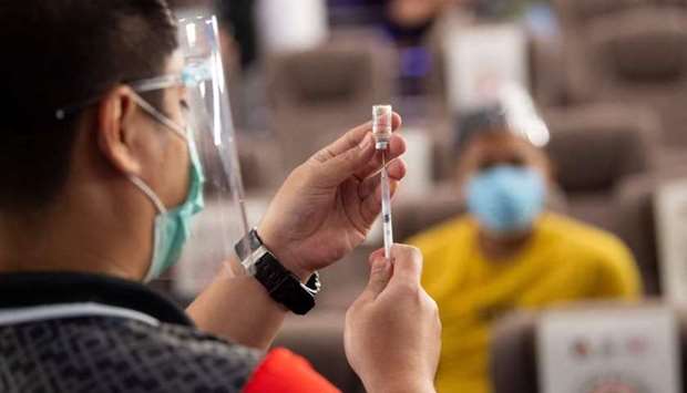 A health worker (L) prepares a vial of Chinese Sinovac vaccine against Covid-19 coronavirus inside a movie theatre turned into a vaccination centre in Taguig City suburban Manila on June 14. AFP