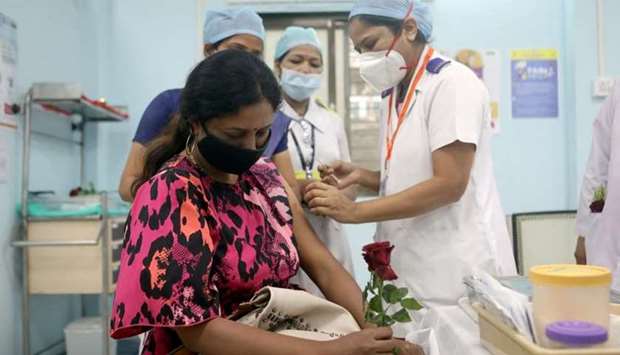 A healthcare worker holding a rose receives an AstraZeneca's Covishield vaccine, during the coronavirus disease vaccination campaign, at a medical centre in Mumbai, India on January 16. REUTERS