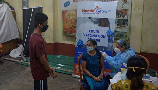 A health worker inoculates a woman with a jab of Covishield's Covid-19 Coronavirus vaccine at a club in Siliguri after India opened up free vaccinations to all adults in an attempt to bolster its inoculation drive.