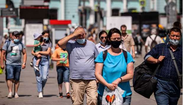 People wearing face masks walk down a street in Moscow