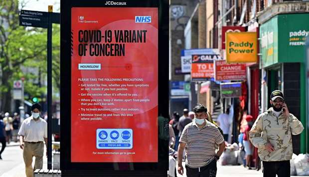 Pedestrians walk past a sign warning members of the public about the spread of Coronavirus, as they walk along the street in Hounslow, west London