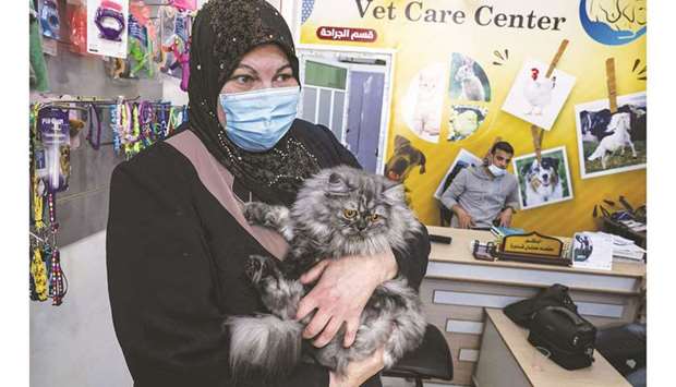 Palestinian cat owner Amani Abu Shaaban holds her feline companion while waiting at a veterinary clinic in Gaza City.