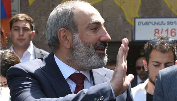 Armenia's acting Prime Minister Nikol Pashinyan waves as he walks to vote at a polling station during early parliamentary elections in Yerevan on June 20