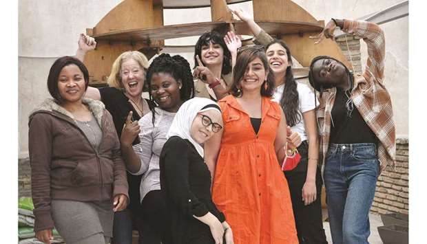 Greek and refugee women, along with co-ordinator Amie Williams (second left), participating in a project on gender equality, cheer at the office of an organisation in Athens. (AFP)