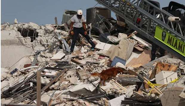 A Miami-Dade Fire Rescue person and a K-9 continue the search and rescue operations in the partially collapsed 12-story Champlain Towers South condo building on June 24 in Surfside, Florida