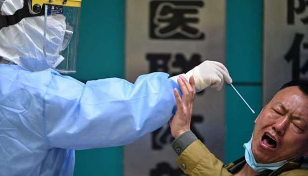 In this photo taken on April 16, 2020 a man being tested for the Covid-19 novel coronavirus reacts as a medical worker takes a swab sample in Wuhan, in China's central Hubei province. AFP