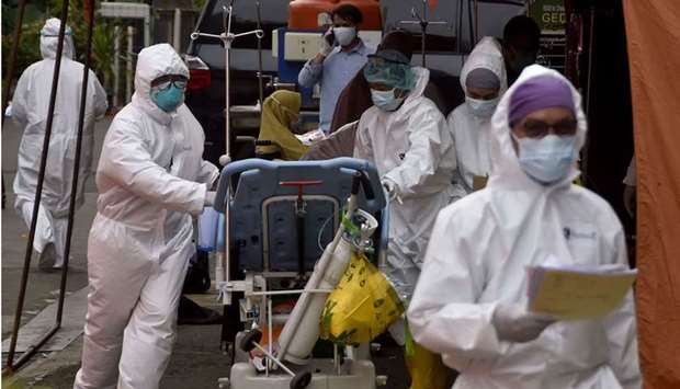 Health workers clad in protective gear move a patient who was tested positive for the Covid-19 coronavirus into a hospital in Bekasi as new infections soar to record levels in Indonesia.