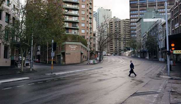 A pedestrian crosses an empty intersection at morning commute hour in the city centre during a lockdown to curb the spread of a coronavirus disease (Covid-19) outbreak in Sydney, Australia