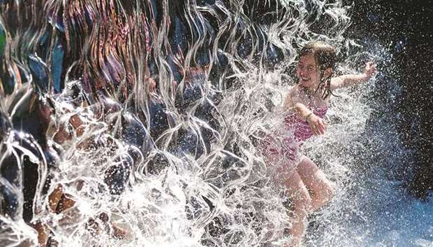 A young girl splashes through a waterfall at a park in Washington, DC, yesterday. (AFP)