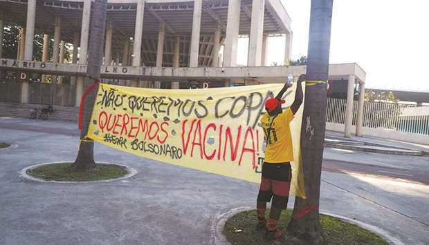 A man adjusts a protest banner reading u201cwe donu2019t want the Cup, we want vaccine! Out Bolsonarou201d outside the Maracana stadium in Rio de Janeiro, Brazil on Wednesday. (Reuters)