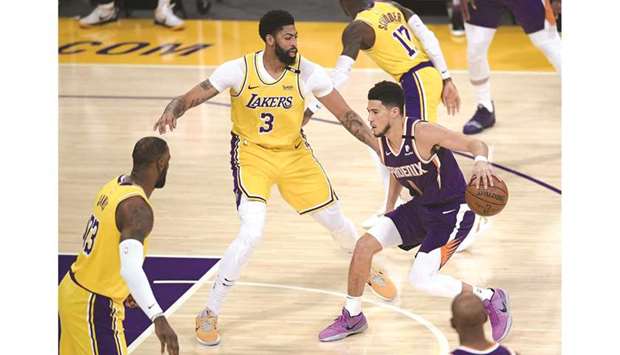 Devin Booker (right) of the Phoenix Suns dribbles in front of Anthony Davis (centre) and LeBron James (left) of the Los Angeles Lakers during game six of the Western Conference first round series at Staples Center in Los Angeles, California, United States, on Thursday. (AFP)