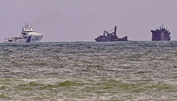 An Indian Coast Guard ship (left) approaches near the Singapore-registered container ship MV X-Press Pearl that partially sunk after burning for almost two weeks, just outside Colombou2019s harbour yesterday, as foreign experts have been deployed to help Sri Lanka contain a potential oil leak from the burnt-out container ship.