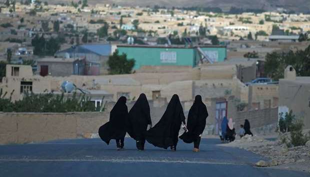 Women walk through a road in Ghazni