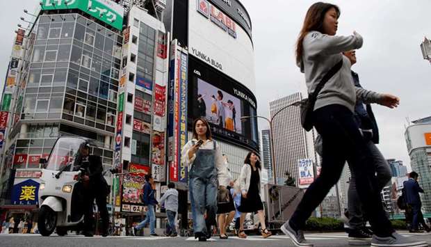 People cross a street in the Shinjuku shopping and business district in Tokyo, Japan
