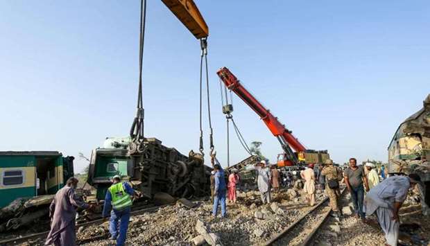 Railway labourers work to clean the wreckage from a railroad track in Daharki, a day after a packed inter-city train ploughed into another express that had derailed.