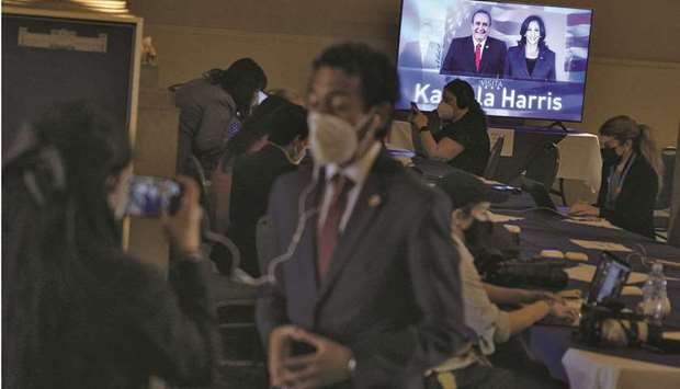 Members of the media work as a screen shows an image of Harris and Giammattei, in Guatemala City.