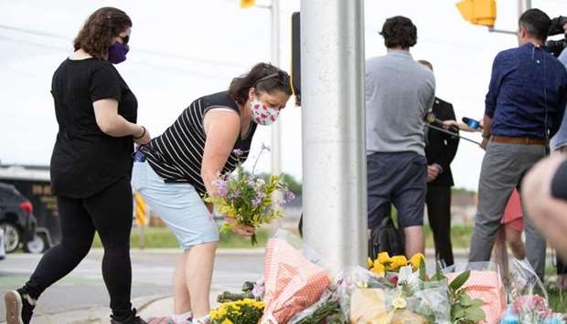 People pay their respects at the scene where a man driving a pickup truck struck and killed four members of a Muslim family in London, Ontario, Canada