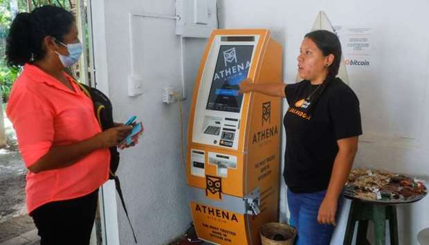 An employee at a Bitcoin support office explains how to make a transaction to a woman at El Zonte Beach in Chiltiupan, El Salvador