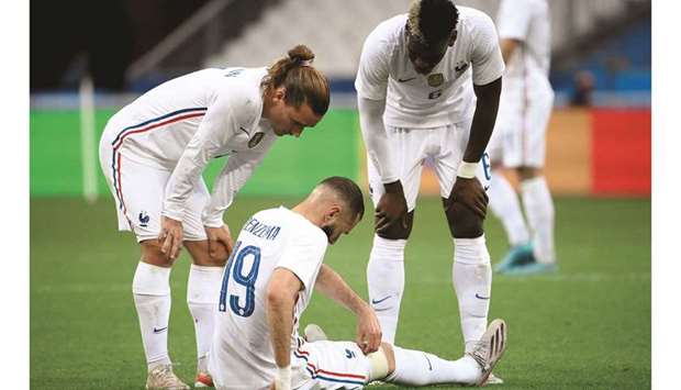 Franceu2019s Antoine Griezmann (left) and Paul Pogba (right) talk to an injured Karim Benzema during the friendly match against Bulgaria in Paris on Tuesday. (AFP)