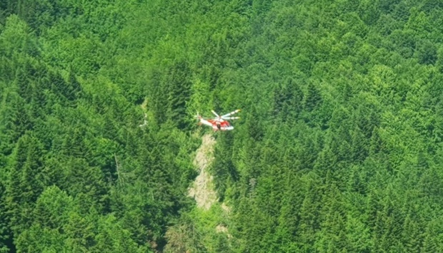 An Alpine Rescue helicopter flies over helicopter crash site near Pievepelago, Italy. Corpo Nazionale Soccorso Alpino e Speleologico/Handout via REUTERS