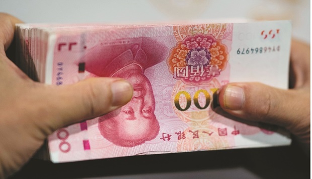 An employee is counting out 100 yuan notes at a bank in Shanghai. Financial institutions offered 1.89tn yuan of new loans in the month, but more than 60% of those loans were short-term, indicating that companies and households are still reluctant to boost borrowing to buy houses or invest.