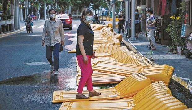 A woman walks over barriers, erected on March 19 according to local residents as part of pandemic lockdowns in the area and taken down earlier in the Jingu2019an district of Shanghai as the city lifted more curbs after two months of heavy-handed restrictions.