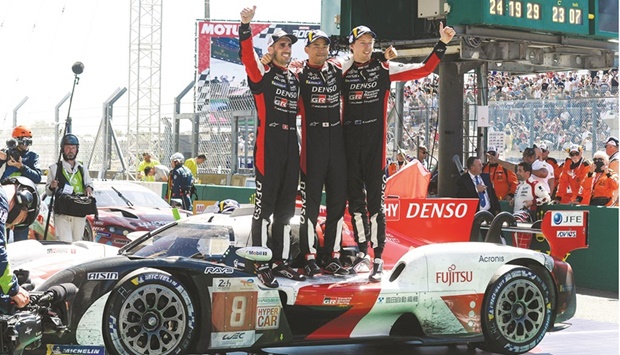 (From left) Drivers of the Toyota number 8 GR010 Hybrid Hypercar Swiss Sebastien Buemi, Japanese Ryo Hirakawa and New Zealander Brendon Hartley celebrate winning the 90th edition of the Le Mans 24 Hours endurance race in Le Mans yesterday. (AFP)