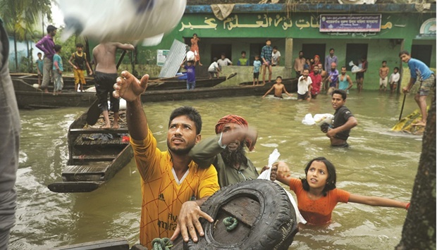 People collect food aid in a flooded residential area following heavy monsoon rainfalls in Companiganj, Bangladesh, yesterday.