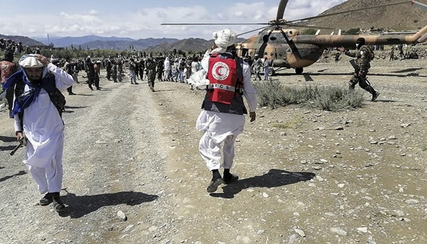 This photograph taken on June 22, 2022 and received as a courtesy of the Afghan government-run Bakhtar News Agency shows soldiers and Afghan Red Crescent Society officials near a helicopter at an earthquake hit area in Afghanistan's Gayan district, Paktika province.