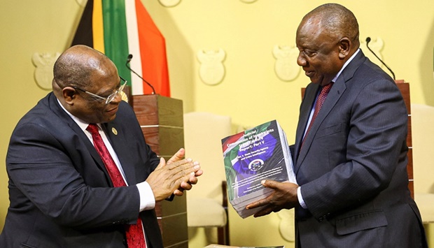 This picture taken on Wednesday shows Ramaphosa receiving the final investigation report from Chief Justice Raymond Zondo at the governmentu2019s Union Buildings in Pretoria.