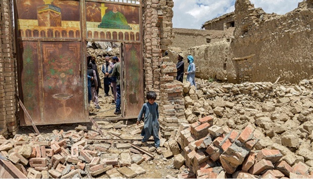 A child walks out from inside a gate of a house damaged by an earthquake in Bernal district, Paktika province.