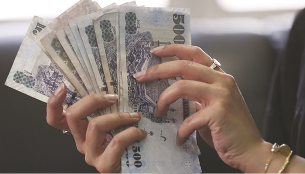 A Saudi woman counts riyal banknotes at a money exchange shop in Riyadh (file). The Saudi Central Bank placed about 50bn riyals ($13bn) as time deposits with commercial lenders, according to people familiar with the matter, seeking to ease the worst liquidity crunch in over a decade.