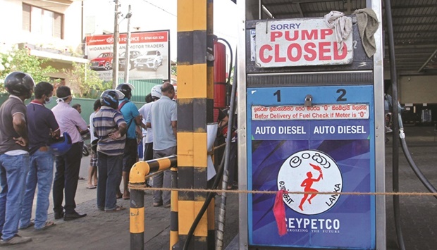 People stand outside a closed Ceylon Petroleum Corporation fuel station that ran out of gasoline in Colombo yesterday.