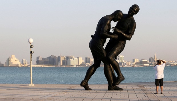 FILE PHOTO: A man takes pictures of a bronze sculpture titled 'Coup de Tete' during its installation on the Corniche in Doha