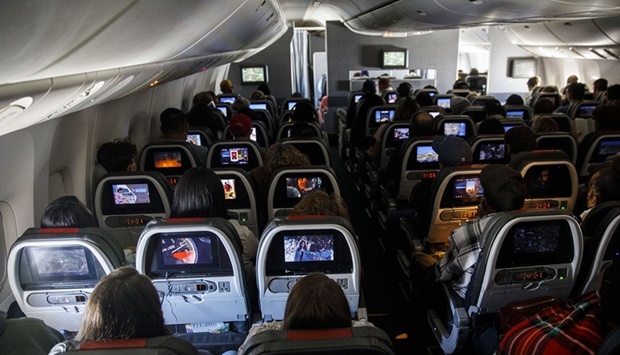 Passengers watch inflight entertainment while sitting in economy class during an American Airlines Group Boeing 777-200 flight from Los Angeles International Airport.